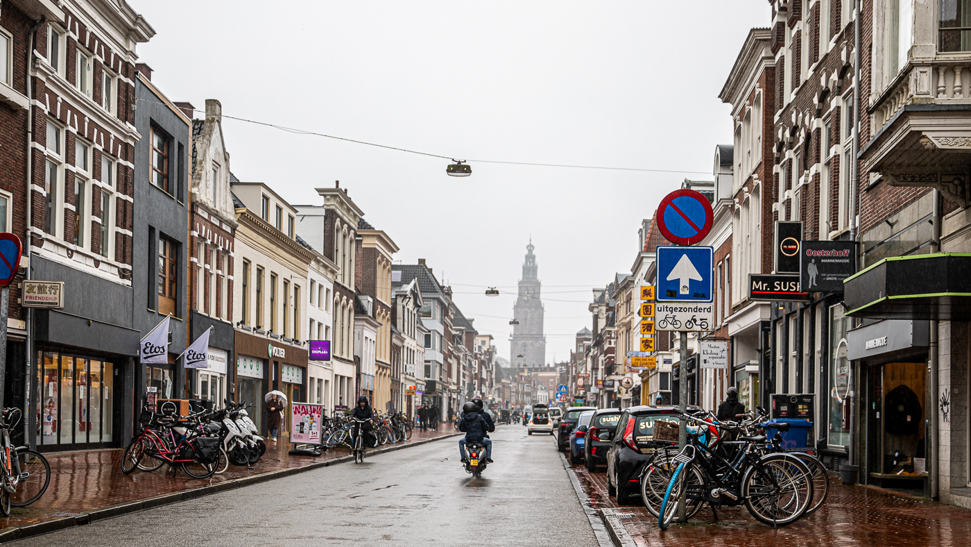 Nieuwe Ebbingestraat in Groningen motorijder midden op de straat met zicht op de Martinitoren